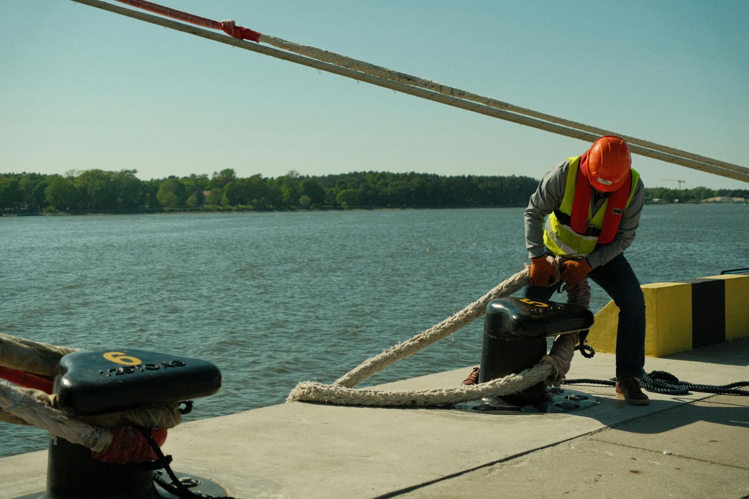 A man in an orange vest is working on a dock